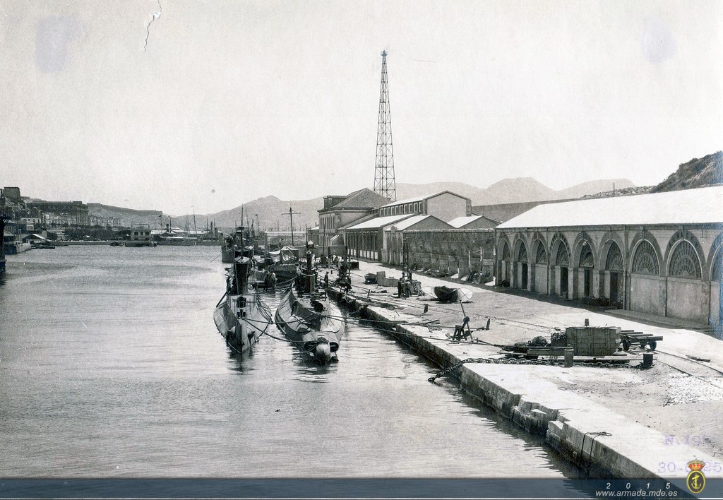 1925. Submarinos clase B en el muelle de armamento de la SECN de Cartagena abarloados proa con popa. A la izquierda de los submarinos, en segundo plano, el antiguo edificio del Club de Regatas. 